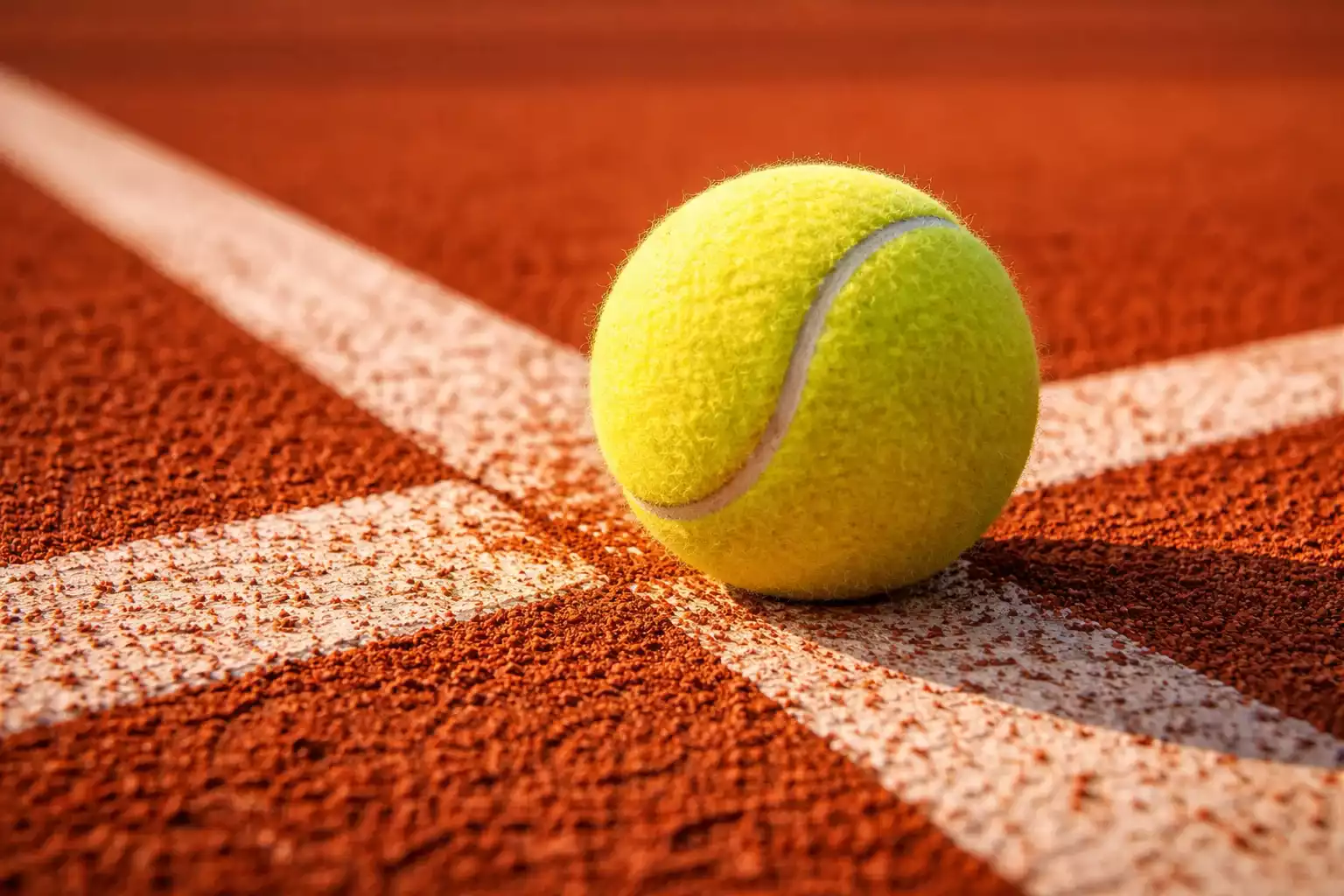 Nahaufnahme eines Tennisballs auf einem Sandplatz mit Linien